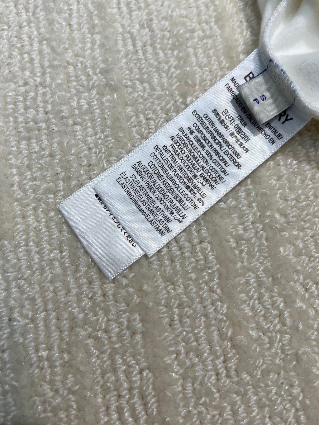 White shirt care label with washing instructions and size markings