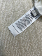White shirt care label with washing instructions and size markings