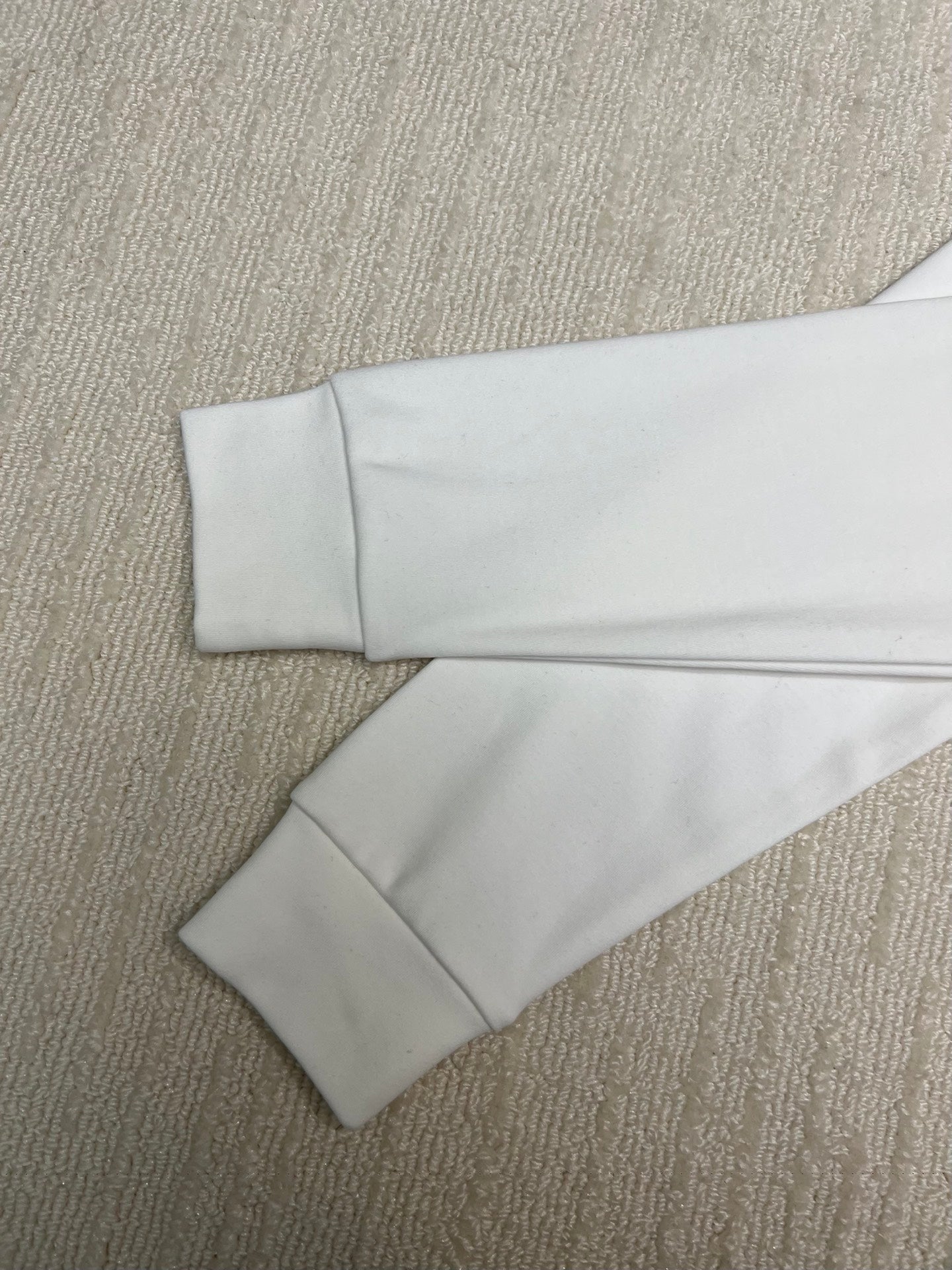 White long-sleeve shirt laid flat showing sleeves and straight hem