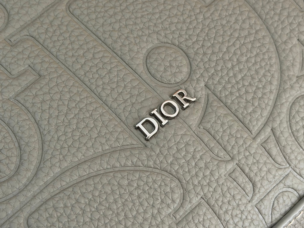 Embossed DIOR logo on gray textured bag material.
