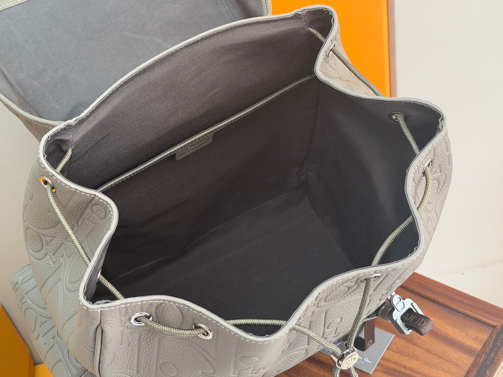 Open gray Dior men’s bag interior with dark lining and side pocket openings.