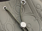 Gray Dior bag with braided strap and circular metal ring detail.