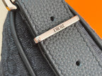 Dior men’s bag close-up of leather strap tab with gold “DIOR” plate