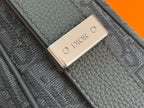 Dior men’s bag close-up of gold “DIOR” logo plaque on textured leather