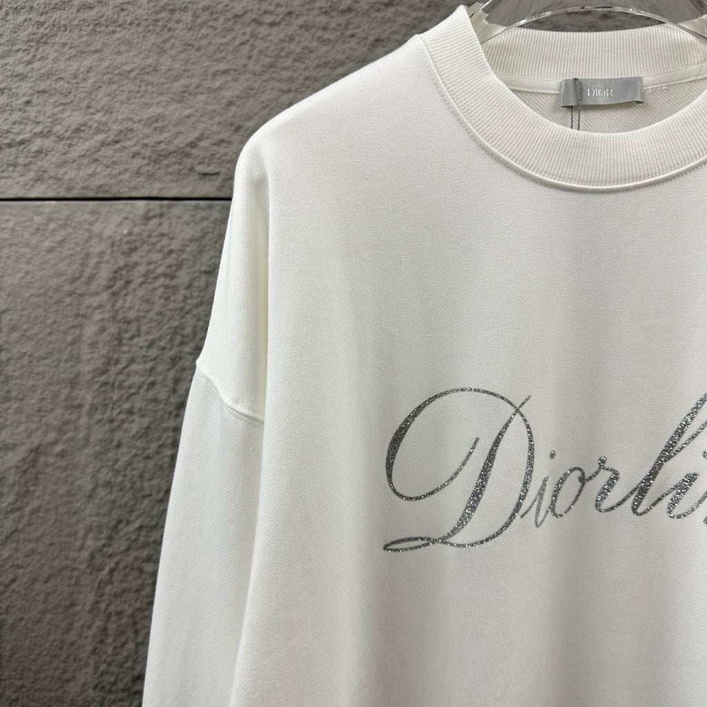 White long-sleeve sweatshirt with ribbed crew neck and partial glitter script logo.