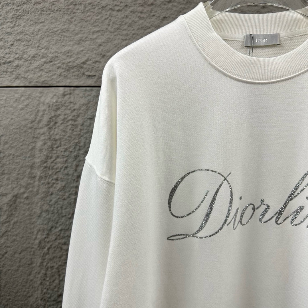 White long-sleeve sweatshirt with ribbed crew neck and partial glitter script logo.