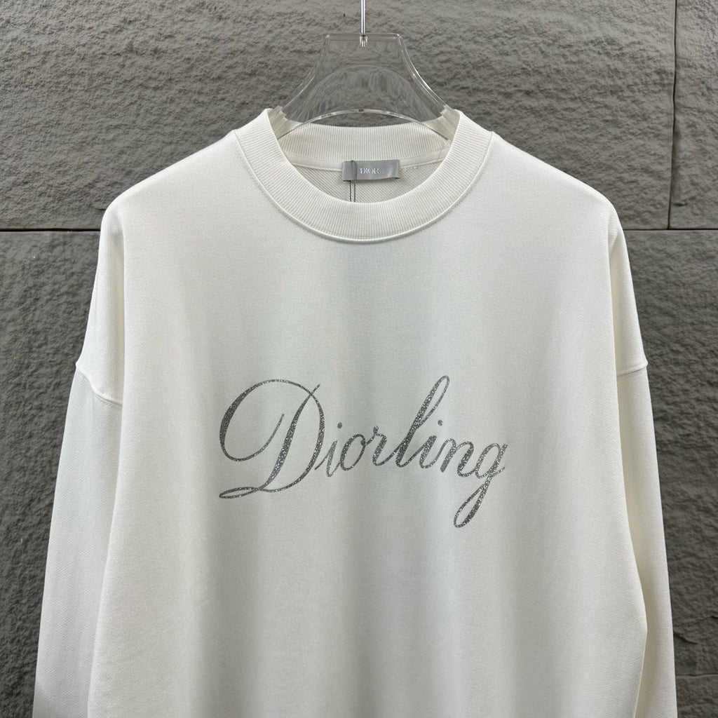 White long-sleeve sweatshirt close-up showing glitter “Diorling” script logo.