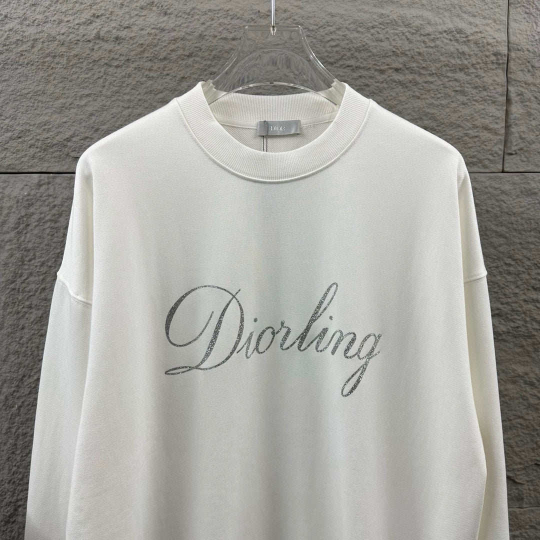White long-sleeve sweatshirt close-up showing glitter “Diorling” script logo.