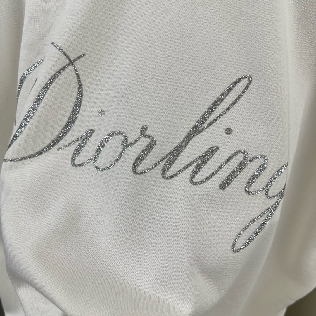 White sweatshirt close-up of glitter “Diorling” script across chest.