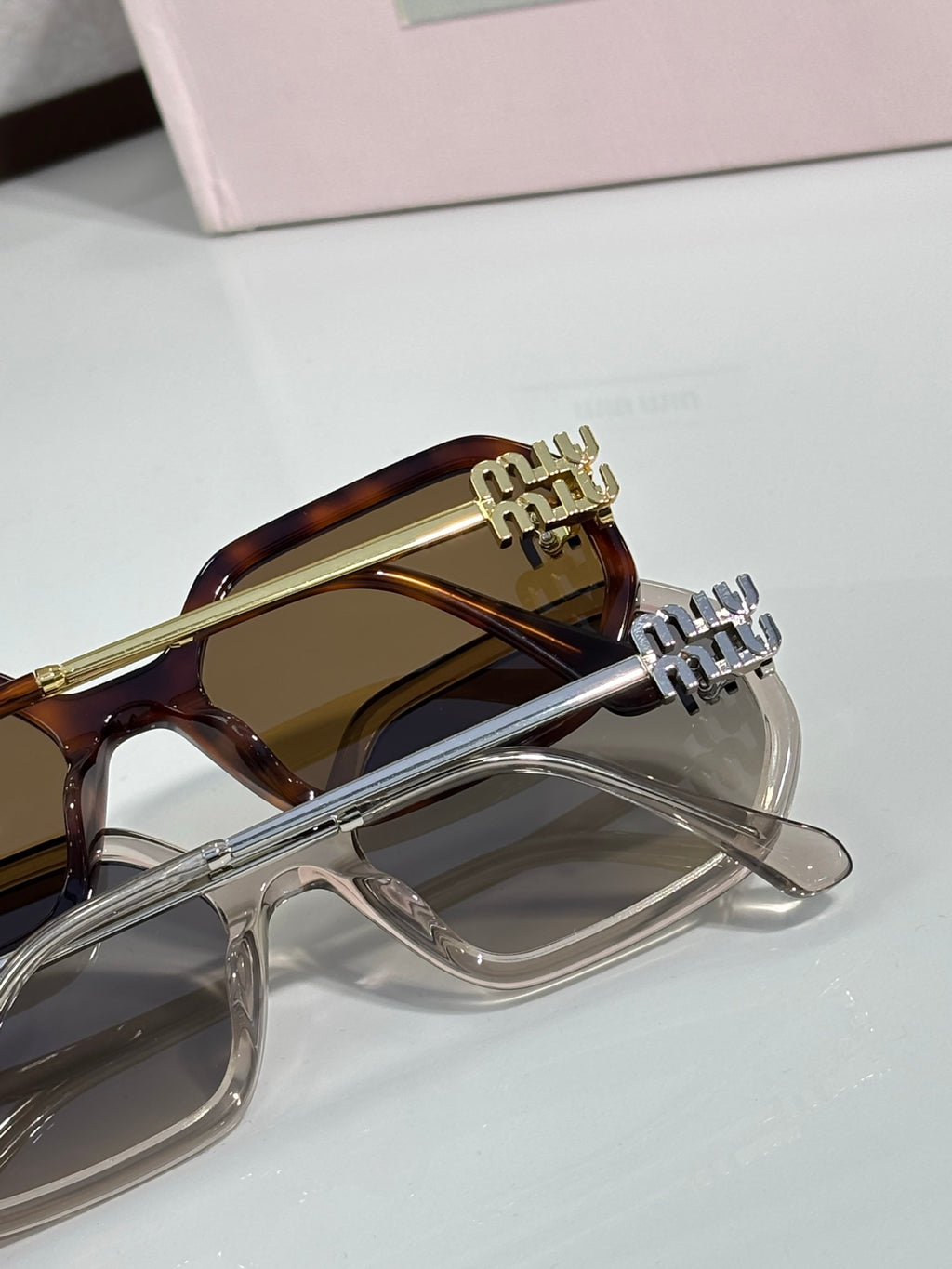 MiuMiu tortoise and clear sunglasses close-up with gold-tone logo arms