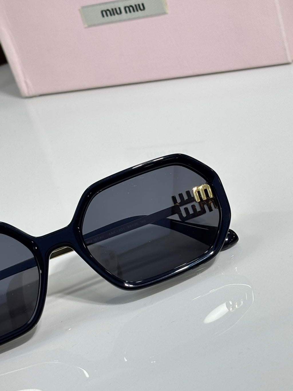 MiuMiu black sunglasses close-up with rectangular frame and logo lens detail