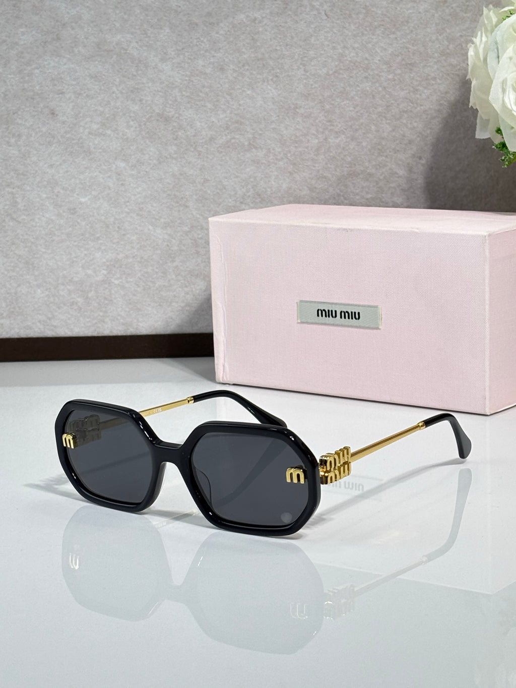MiuMiu black sunglasses with gold-tone arms and dark tinted lenses