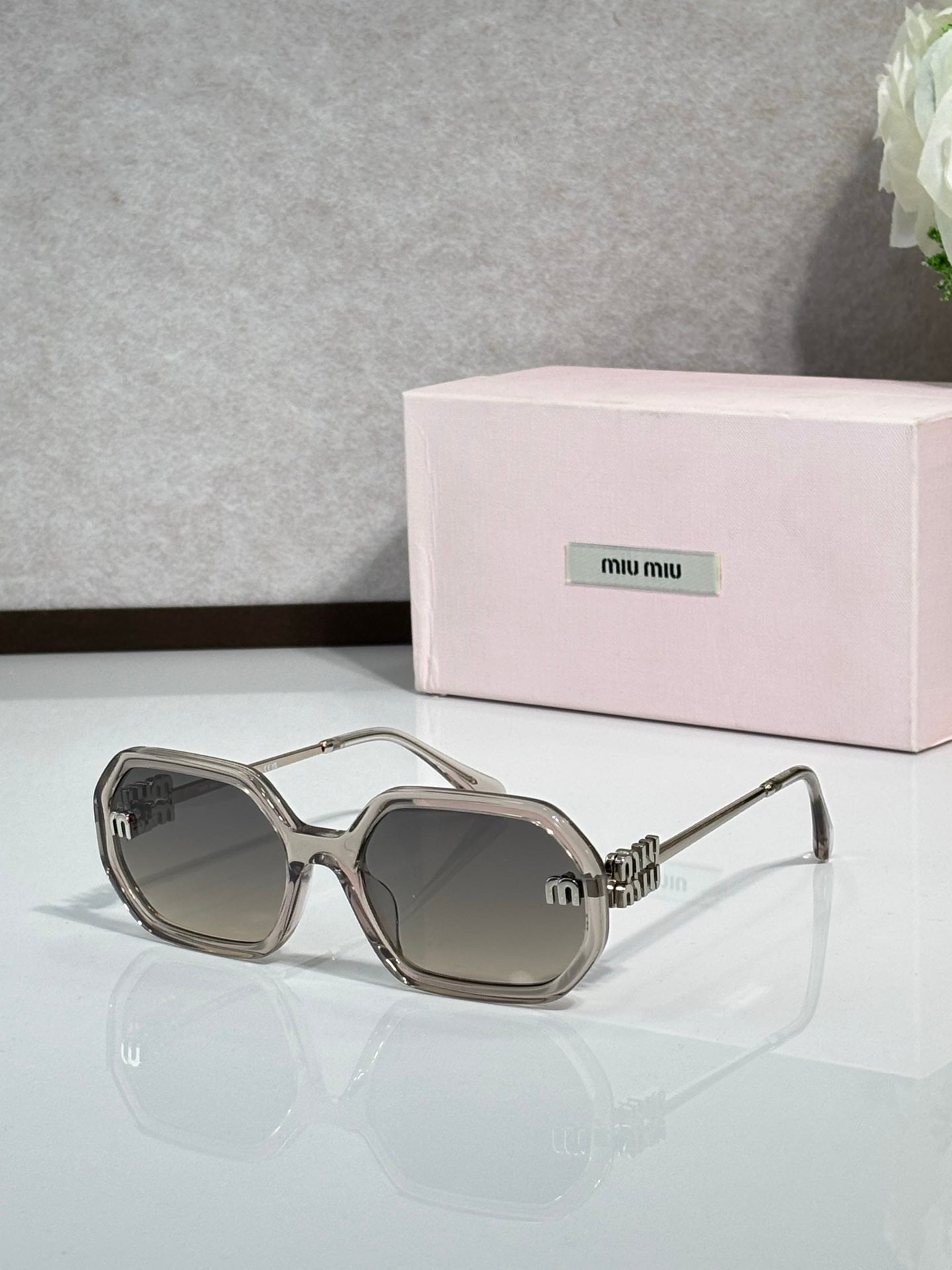 MiuMiu light gray sunglasses with gold-tone arms and dark tinted lenses