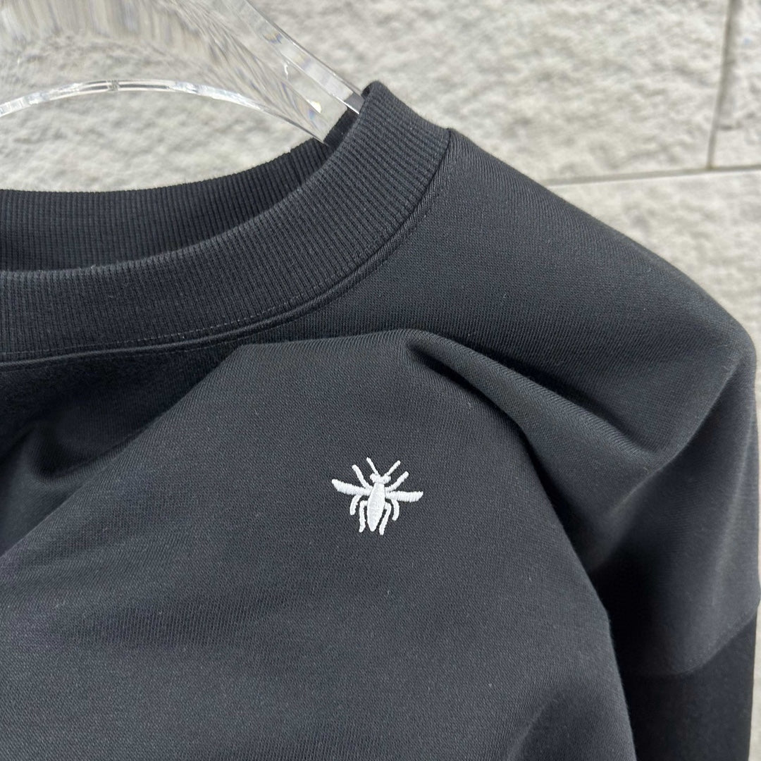 Black crewneck sweatshirt with small white logo on chest and ribbed collar