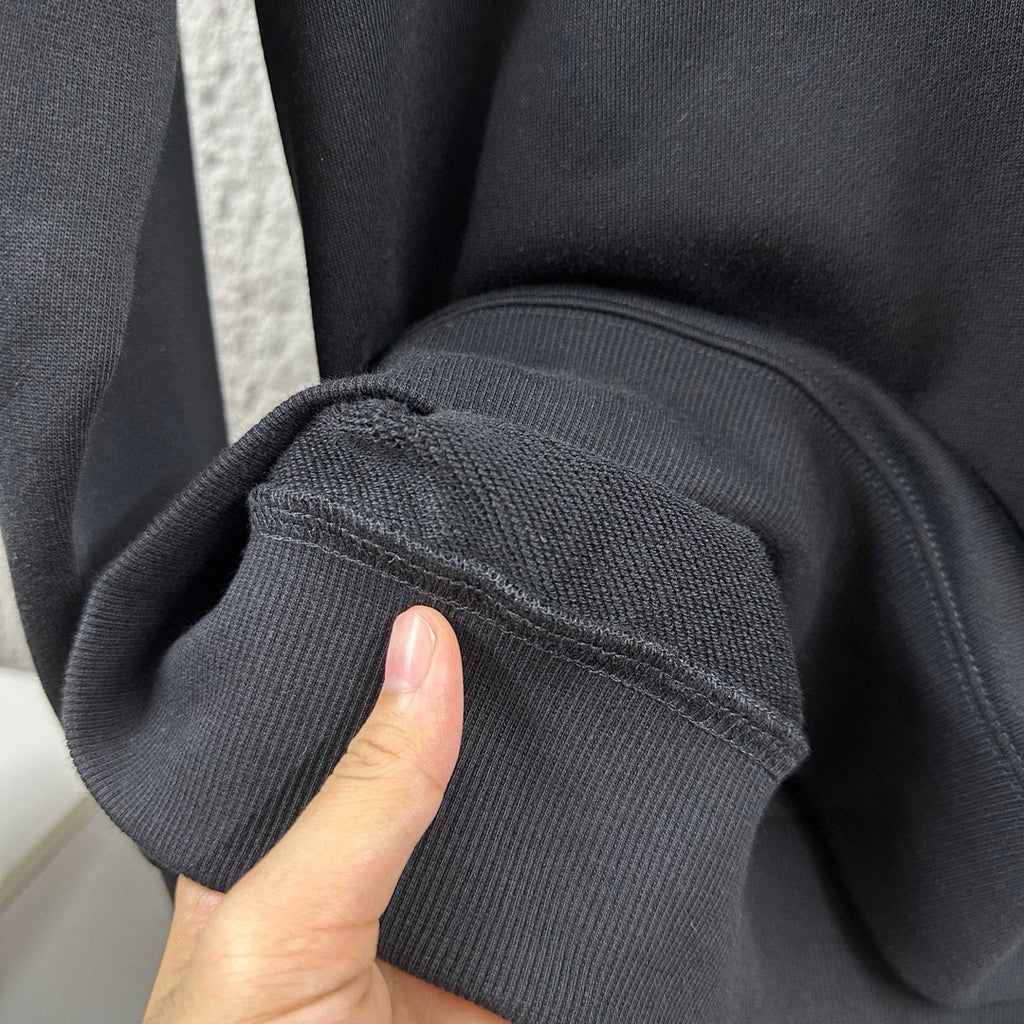 Black sweatshirt sleeve cuff and seam detail near hem