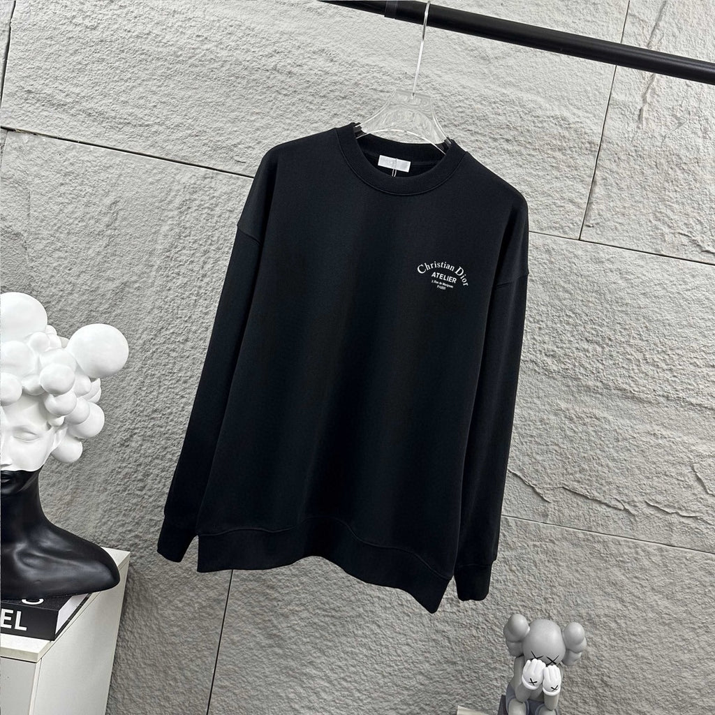 Dark long-sleeve sweatshirt with Christian Dior Atelier chest logo, angled view