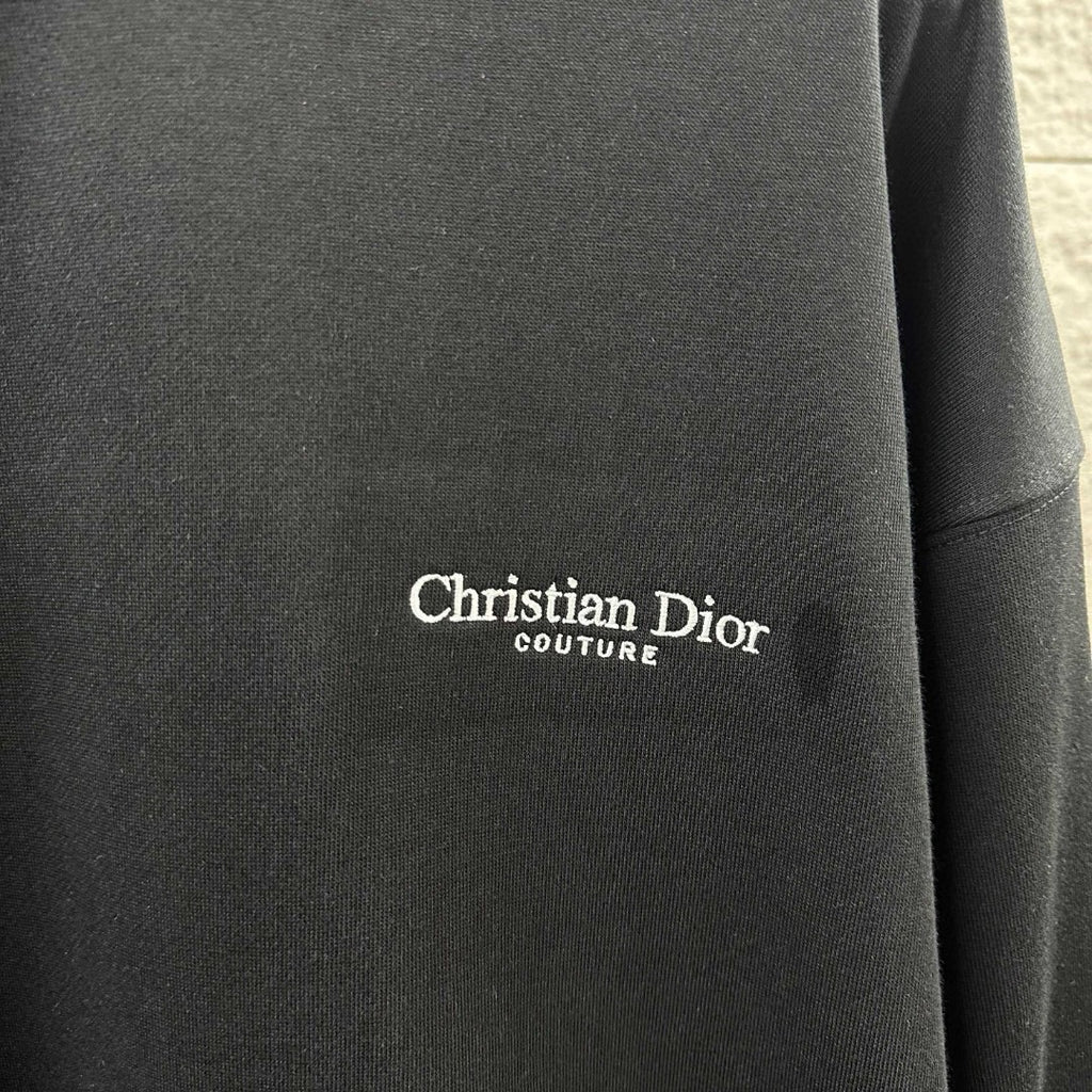 Close-up of Christian Dior Couture logo on black long-sleeve sweatshirt fabric