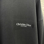 Close-up of Christian Dior Couture logo on black long-sleeve sweatshirt fabric