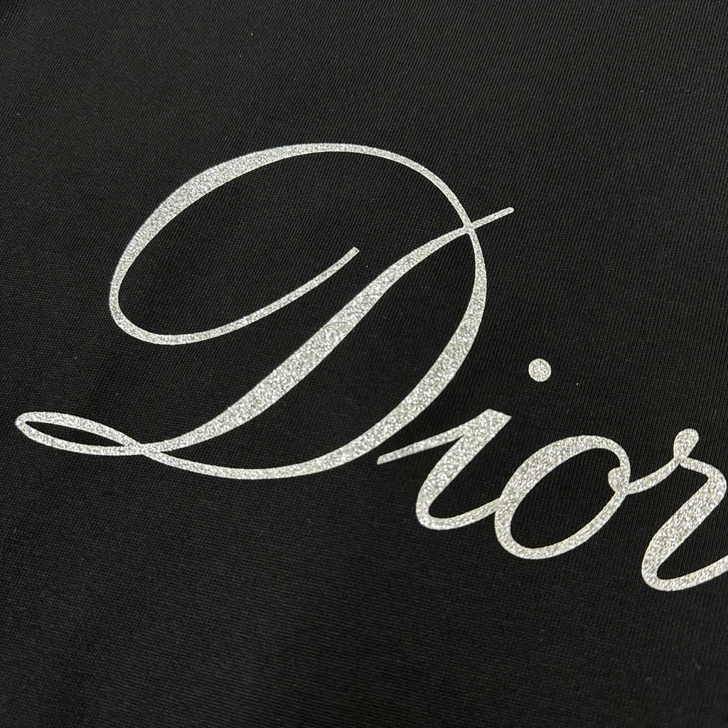 Close-up of “Diortling” white script print on a black T-shirt