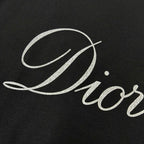 Close-up of “Diortling” white script print on a black T-shirt