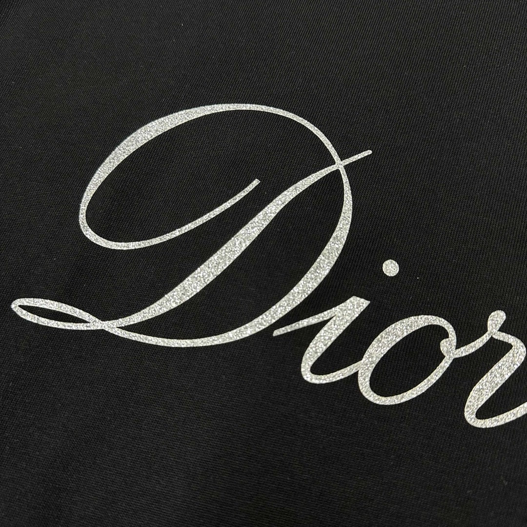 Close-up of “Diortling” white script print on a black T-shirt