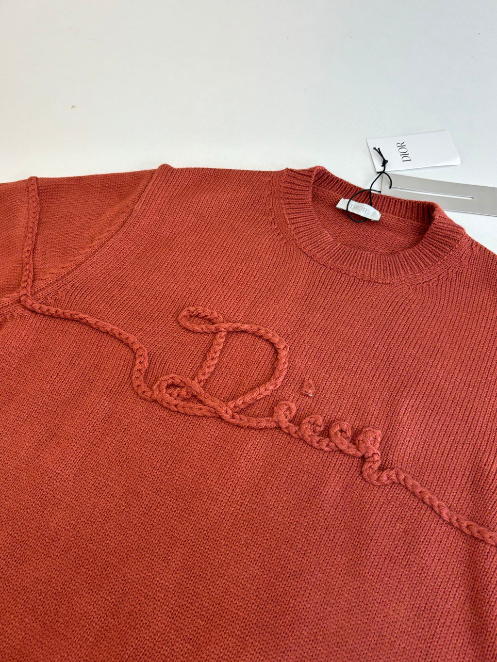 Dior knit sweater chest, rust red, embroidered script logo along the front