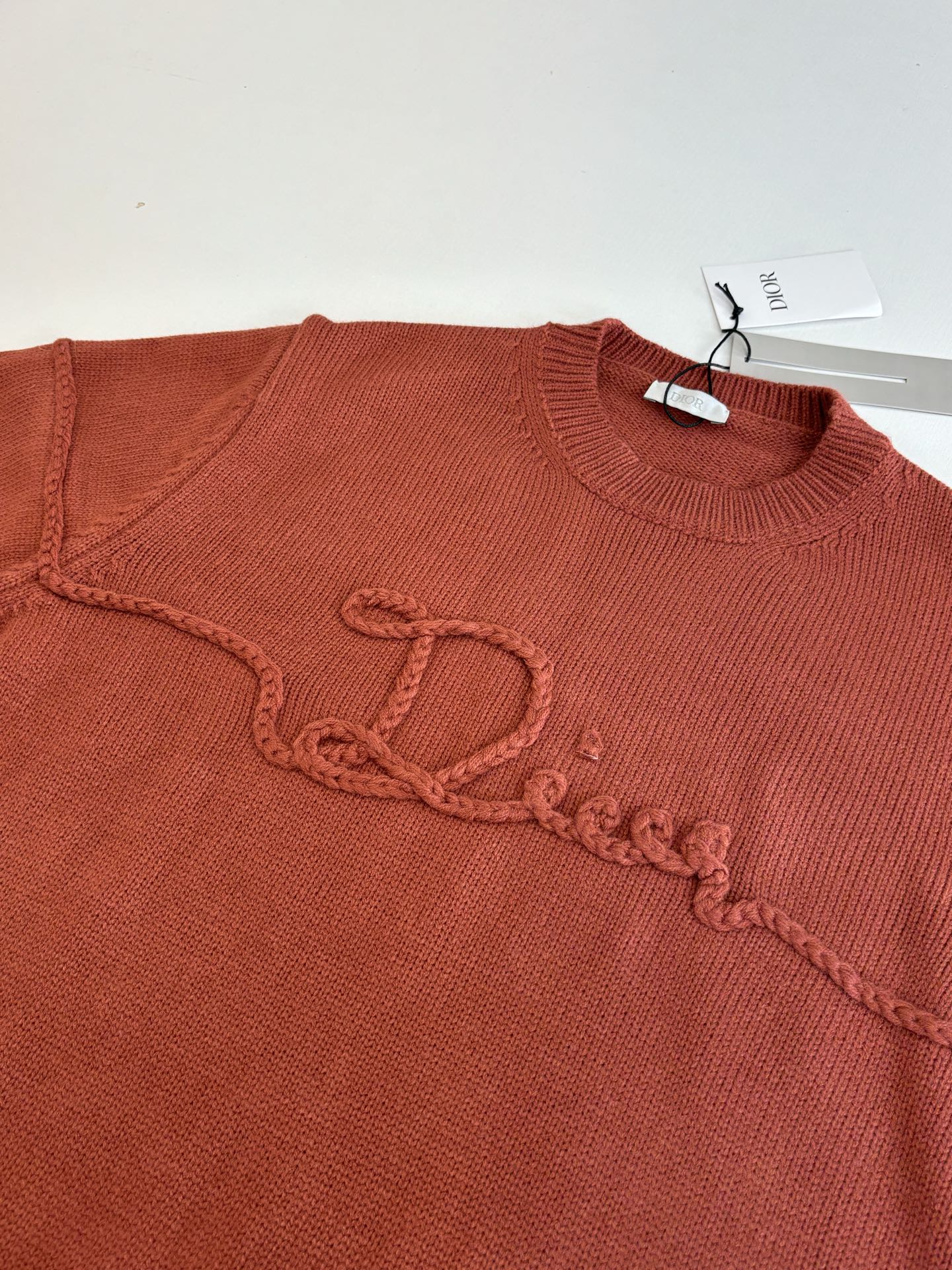 Dior knit sweater chest, rust red, embroidered script logo along the front