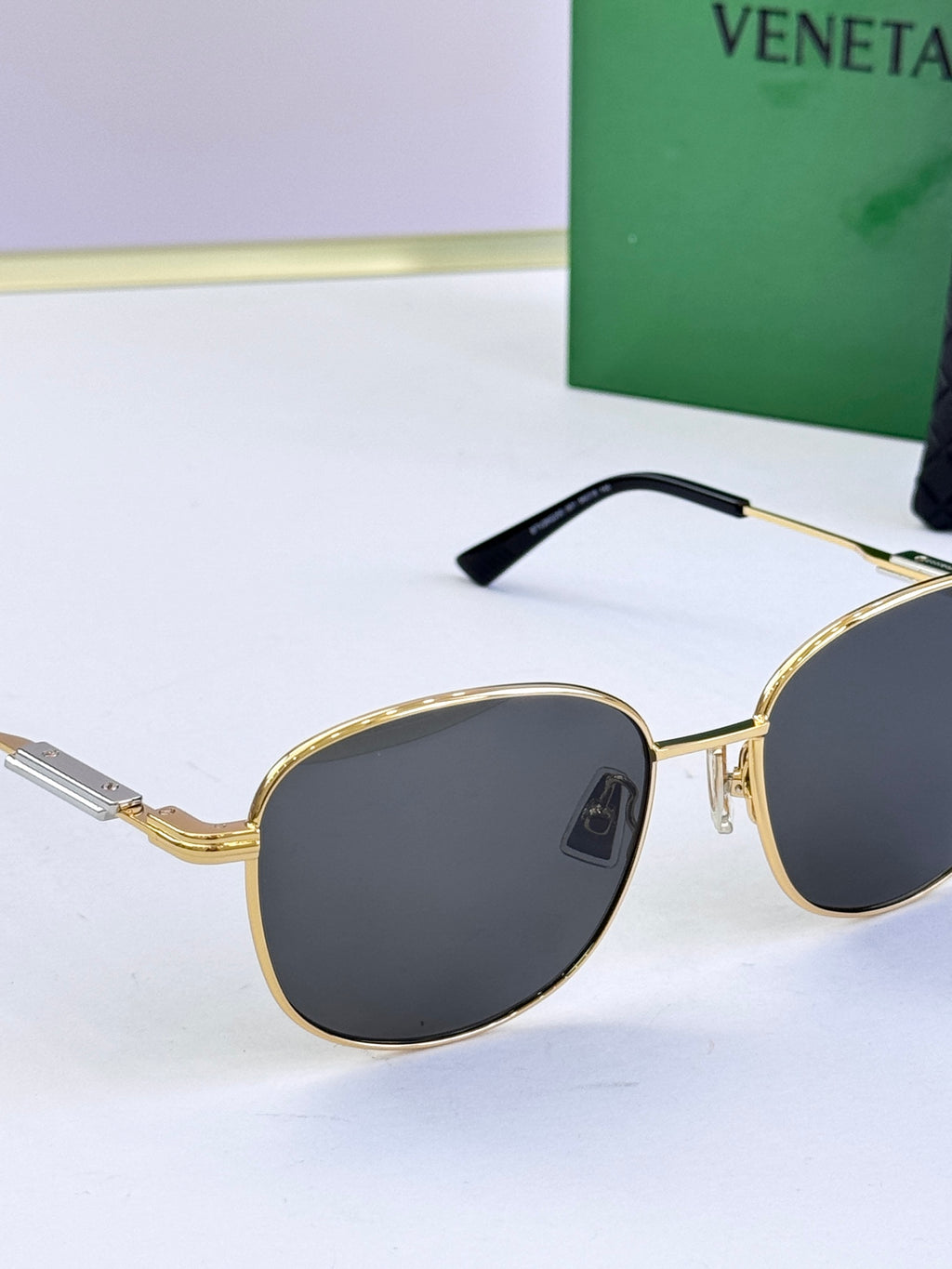 Round sunglasses close-up with dark gray lenses and gold metal frame
