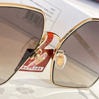 Gucci sunglasses close-up: gold frame with gradient lens edge and logo charm