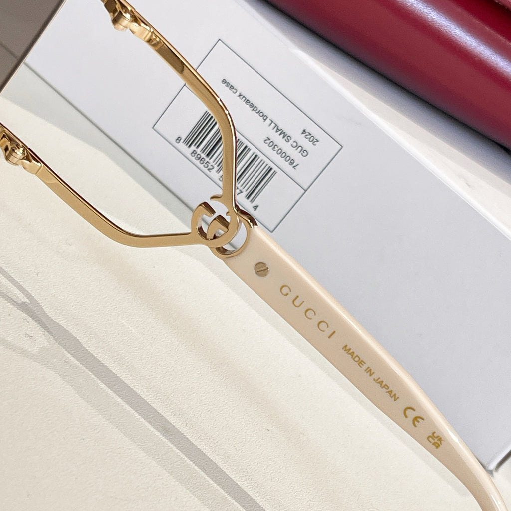 Gucci sunglasses close-up: gold frame and white temple with Gucci text