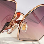 Sunglasses close-up of rose-gold bridge and hinge with purple tinted lenses.