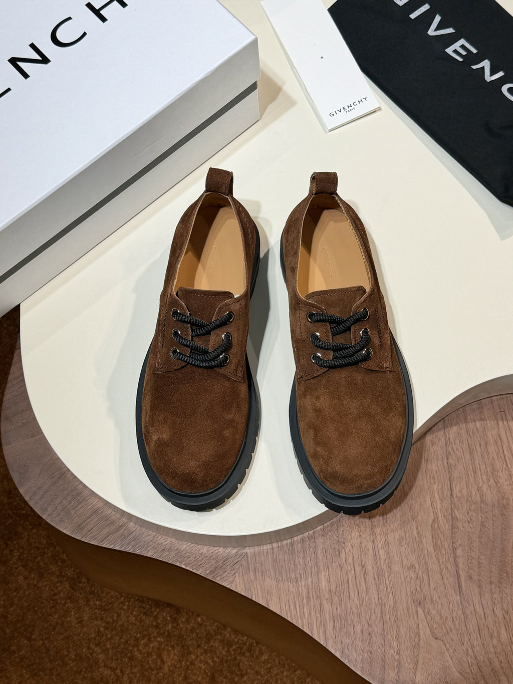 Brown suede lace-up shoes with black trim soles and lace eyelets