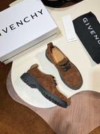 Pair of brown suede lace-up shoes with black rubber soles and lace eyelets