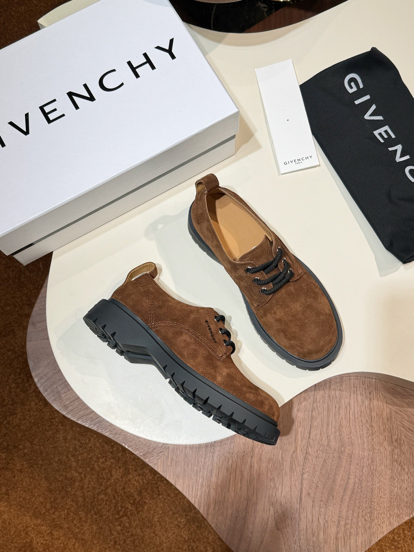 Pair of brown suede lace-up shoes with black rubber soles and lace eyelets