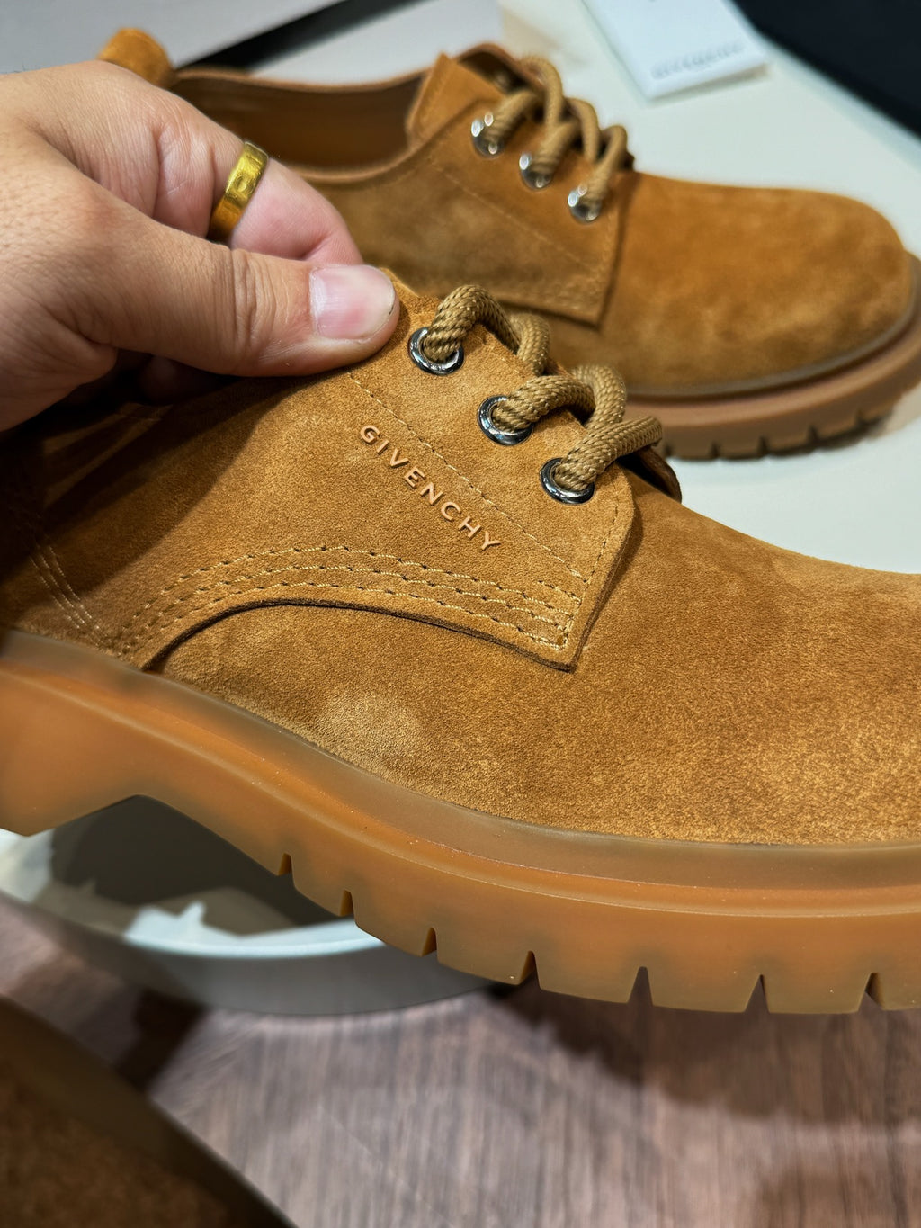 Tan suede lace-up shoes close-up with metal eyelets and logo on tongue