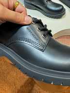 Black leather lace-up shoe close-up, stitched panel and rugged sole edge
