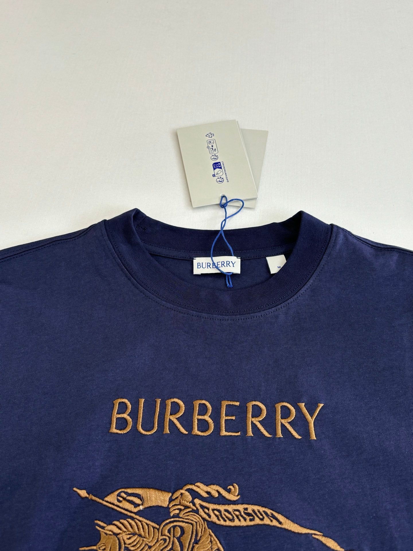 Dark blue short-sleeve T-shirt with Burberry text and gold horse graphic