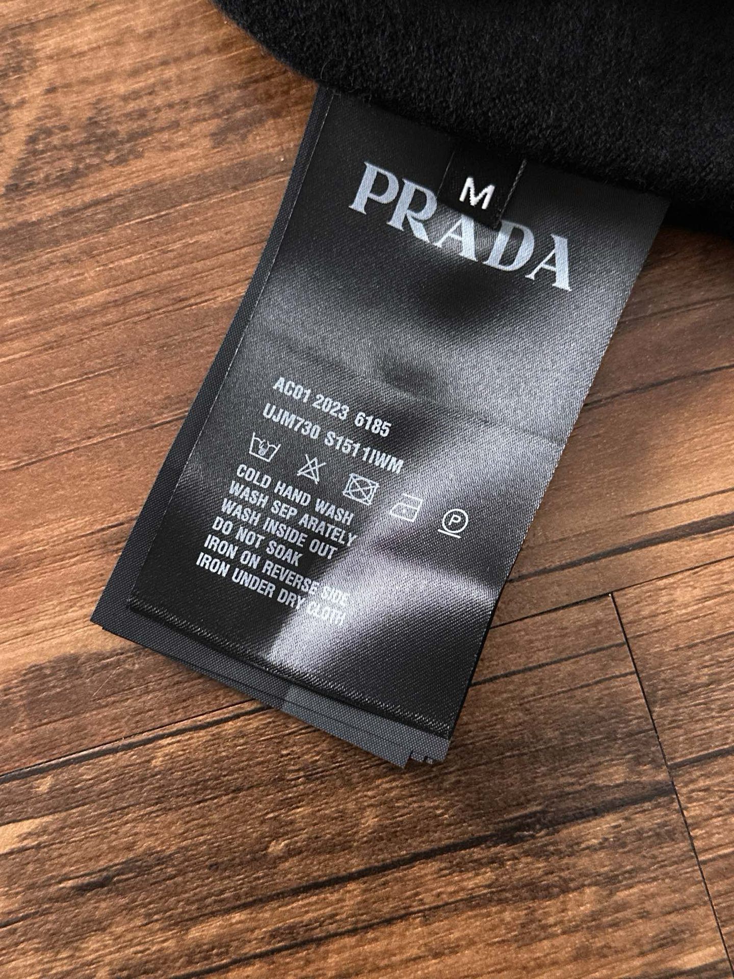 Black fabric label tag with PRADA branding and care instructions