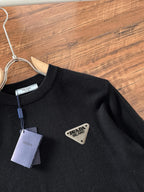 Black crewneck sweater with triangular Prada Milano logo patch on the chest