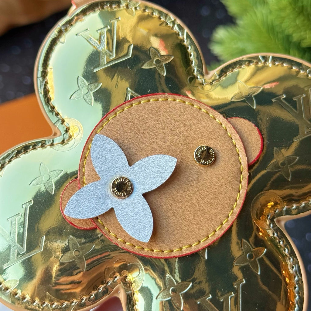 Louis Vuitton close-up of gold flower charm with tan round center and white petal flower