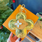 Louis Vuitton small bag keychain charm, gold patterned flower with beige center and metal loop
