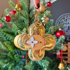 Louis Vuitton gold flower keychain charm hanging on a tree with tan center and white flower