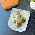 Louis Vuitton gold four-petal keychain charm with tan center and white flower detail