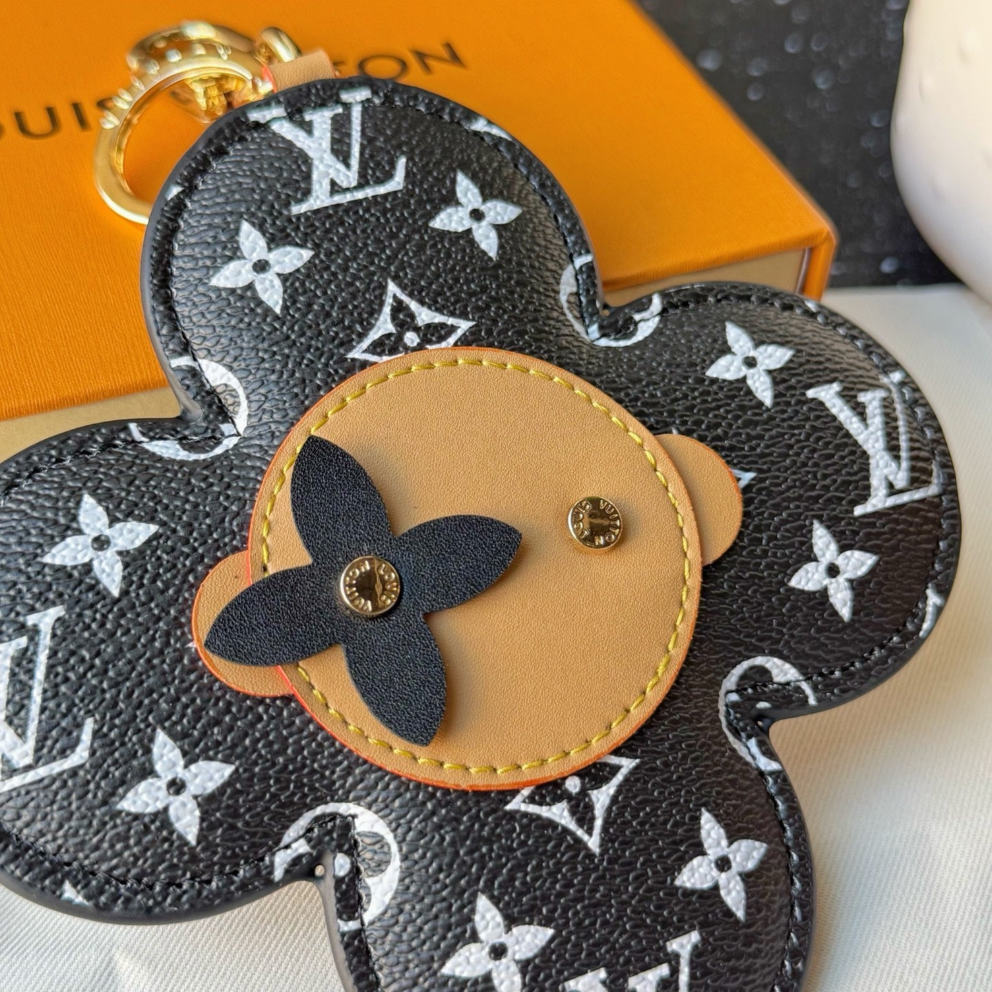 Louis Vuitton monogram flower charm close-up with tan center leather and gold emblem