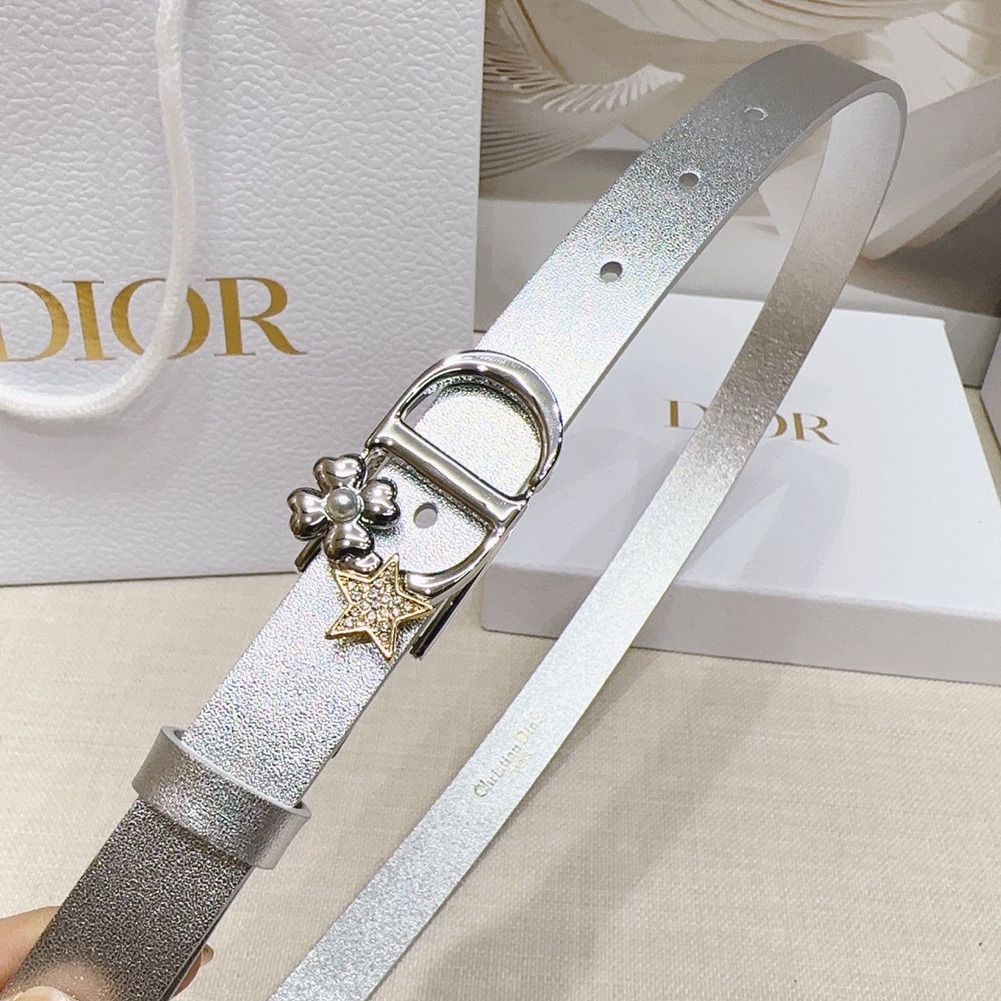 Silver metallic belt detail with oval buckle and star-and-flower charms