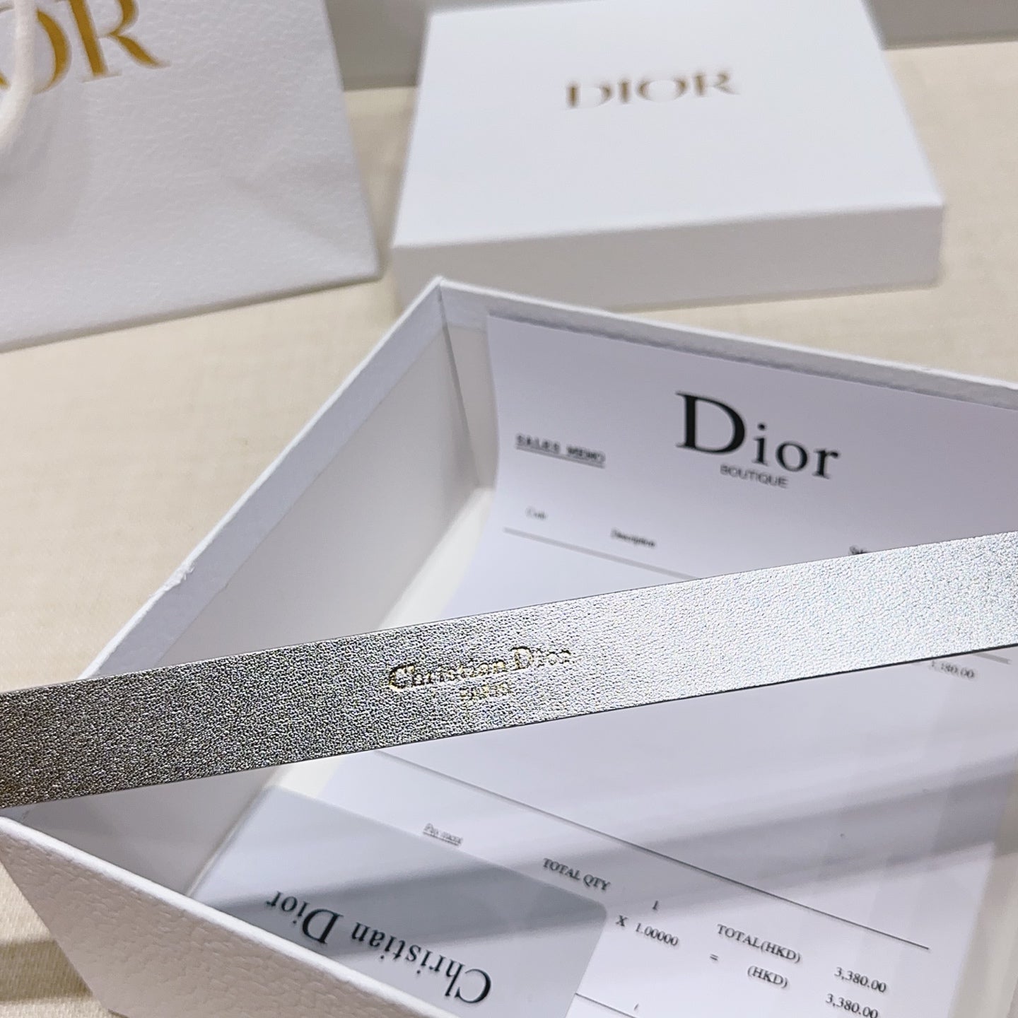 Silver metallic belt strap with visible engraved logo text