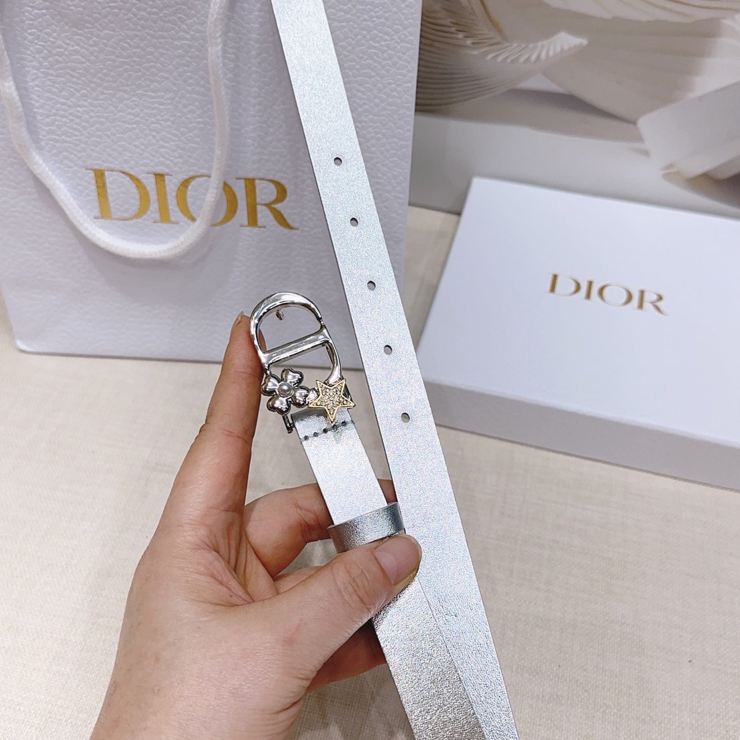 Silver metallic belt with oval buckle and dangling star-and-flower charms