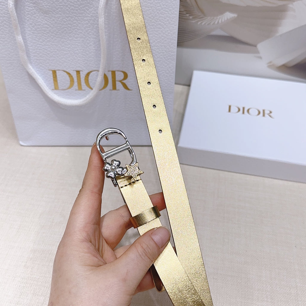Dior belt with gold strap, silver buckle, and star-and-floral charm, held upright.