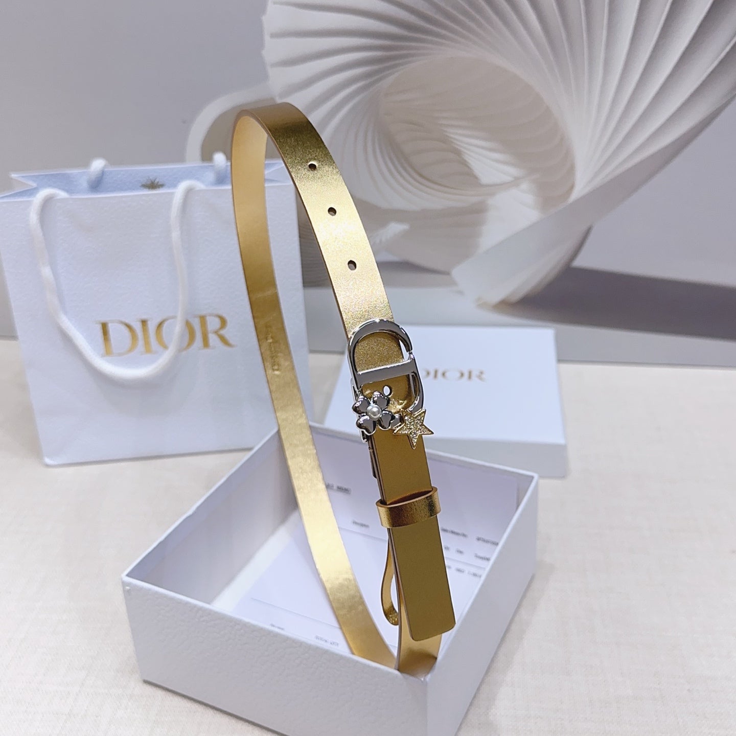 Dior belt in gold leather-look with silver buckle and star charm, shown front side.