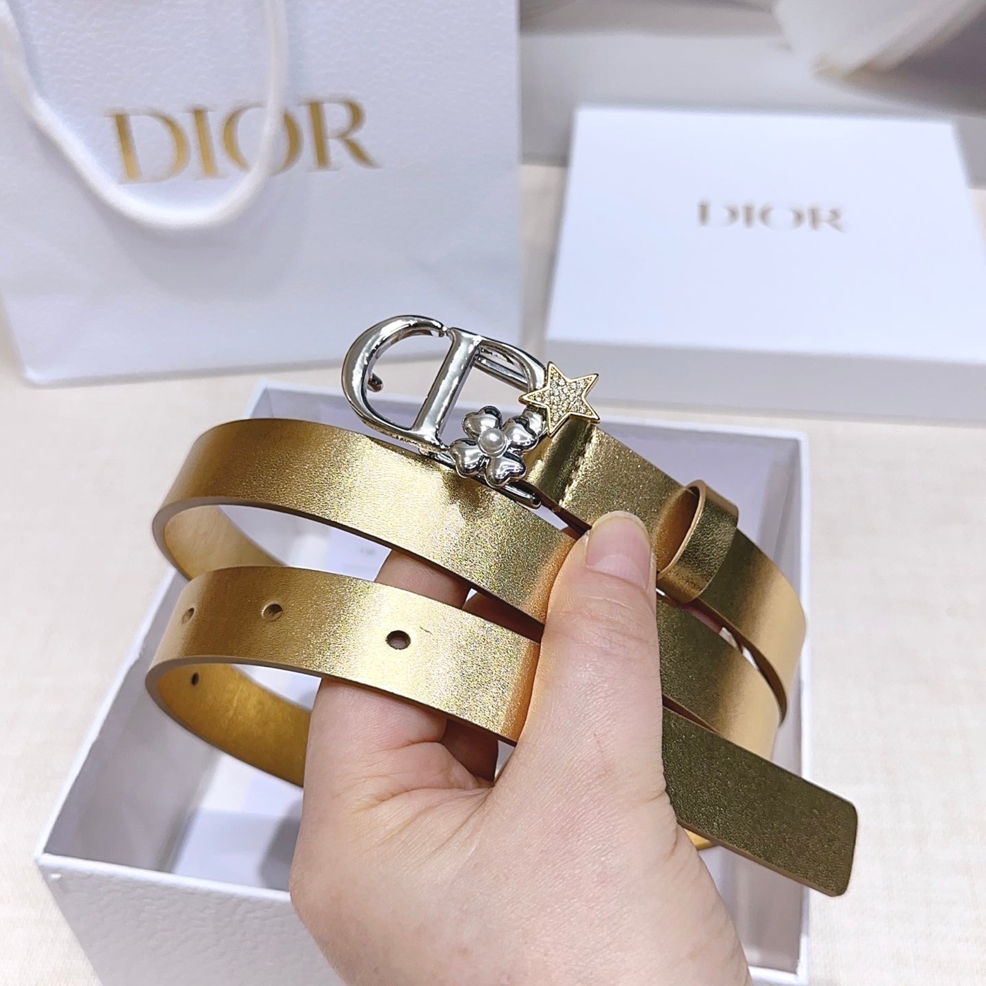 Dior belt in gold leather-look with silver buckle, star charm, and hand-held fit holes.